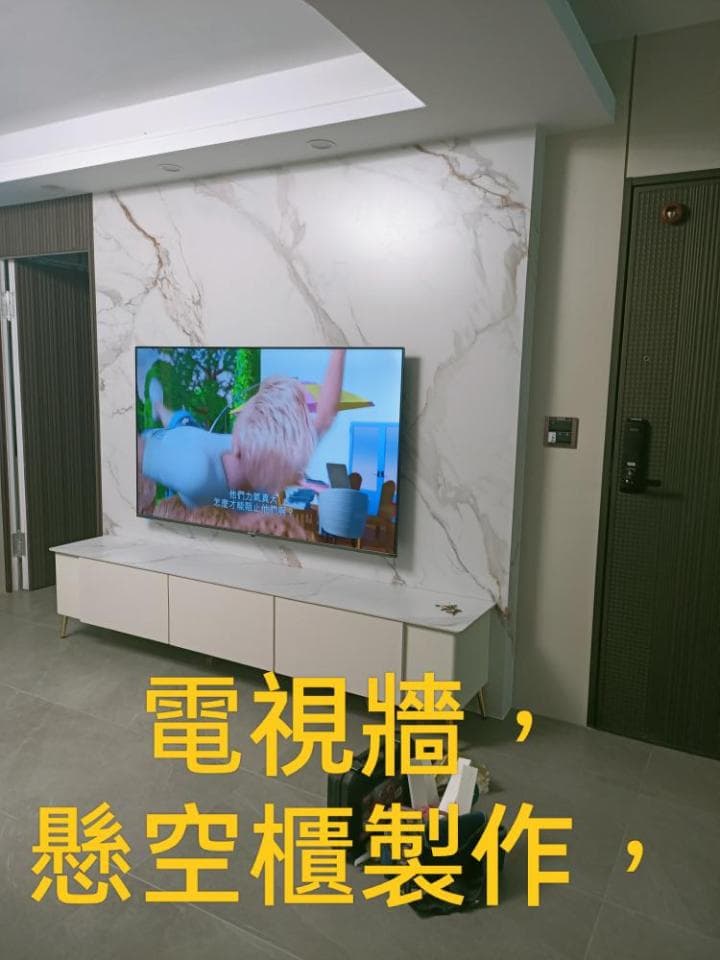 這張照片是一個現代化的客廳,最重要的部分是牆壁上的電視,它被安裝在一个白色的大理石壁架上。