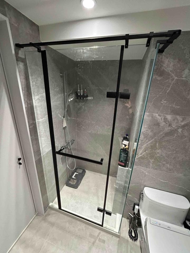 這張照片是現代浴室的淋浴間,黑色框架的玻璃門,配上灰白色磁磚,顯得簡潔時尚。