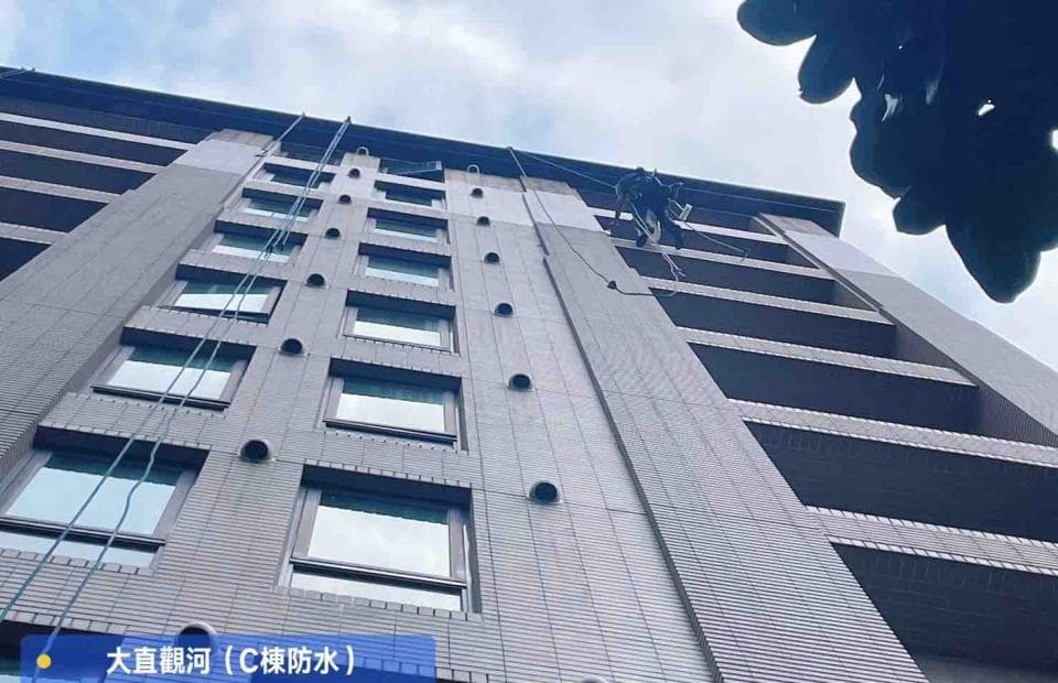 1) 照片顯示一座高樓大廈,大樓外牆有窗戶,有一名工作人員正在進行高空作業