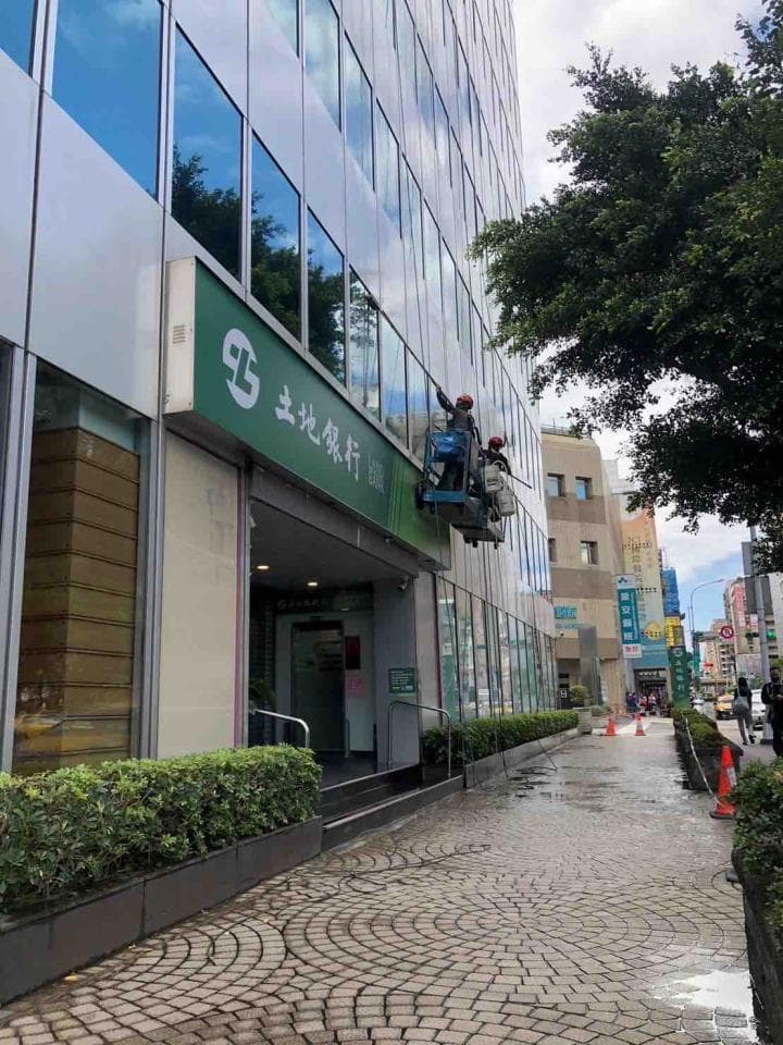 ## 照片資訊
1. **照片描述**: 照片顯示一座高聳的建築物,工人們正在高空作業,清洗外牆的玻璃