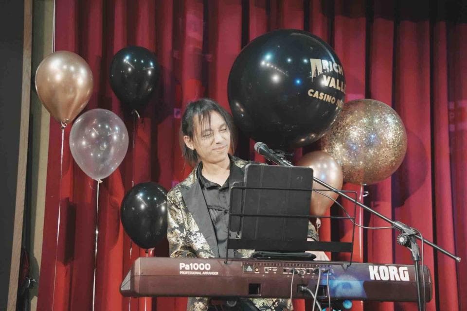 這張照片是一個男子正在彈奏鍵盤,他的周圍有許多氣球。