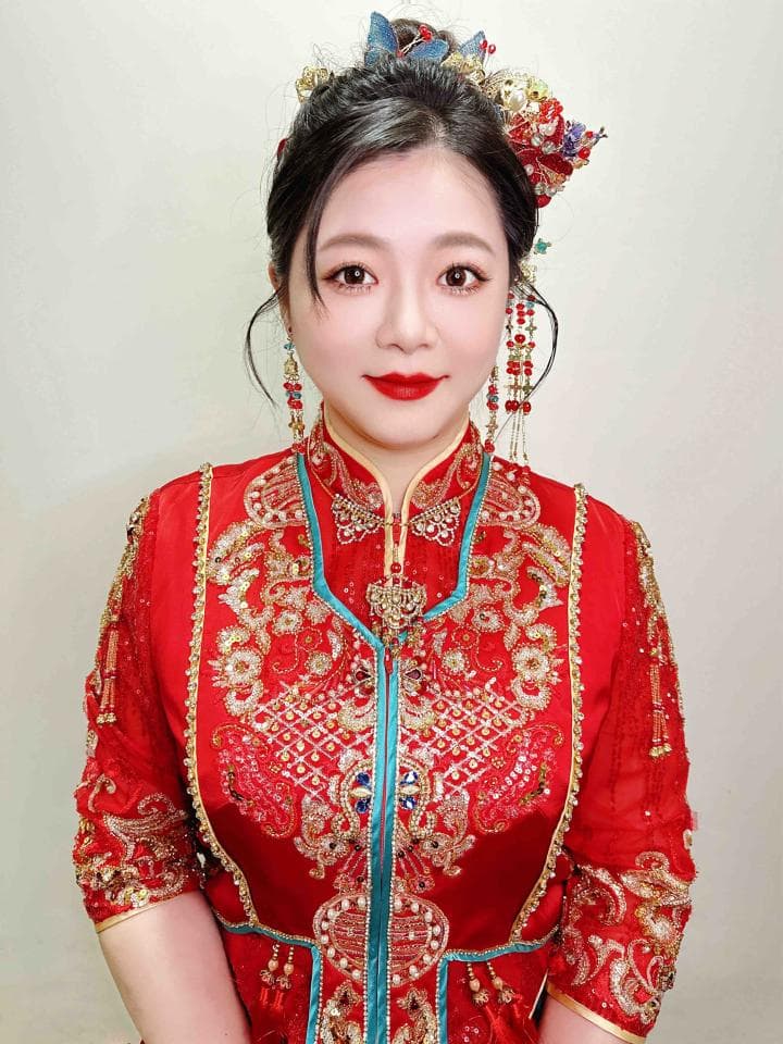 這張照片是一名身穿紅色旗袍的女性。旗袍上繡著精緻的金色花紋,配飾也以金色為主,散發著喜慶的氛圍。