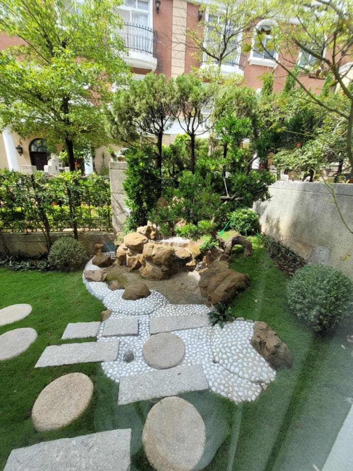 這張「庭園」的照片是一個日式風格的庭園,有石頭步道、白色碎石和綠色植物,還有一個小型的瀑布。