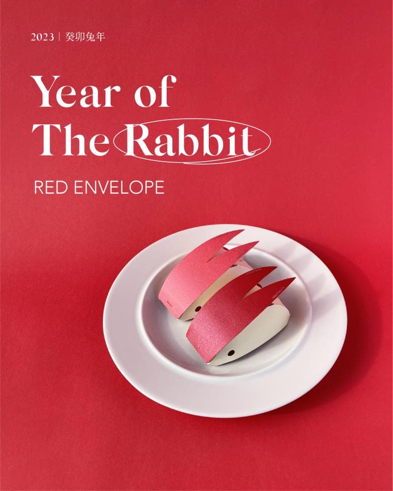 這張照片是兩隻紅色兔子剪紙,放在白色的盤子上。