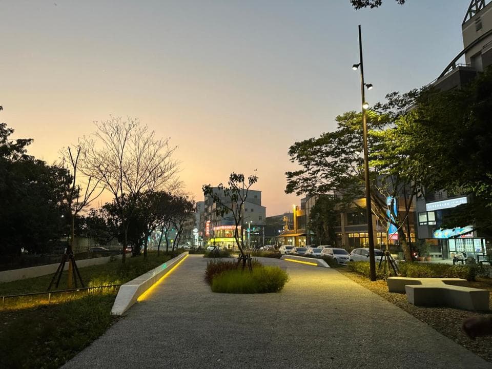 這張「街道夜景」的照片是一條有路燈照亮的步道,旁邊有綠樹和建築物,夕陽餘暉灑在街道上,景色很美。