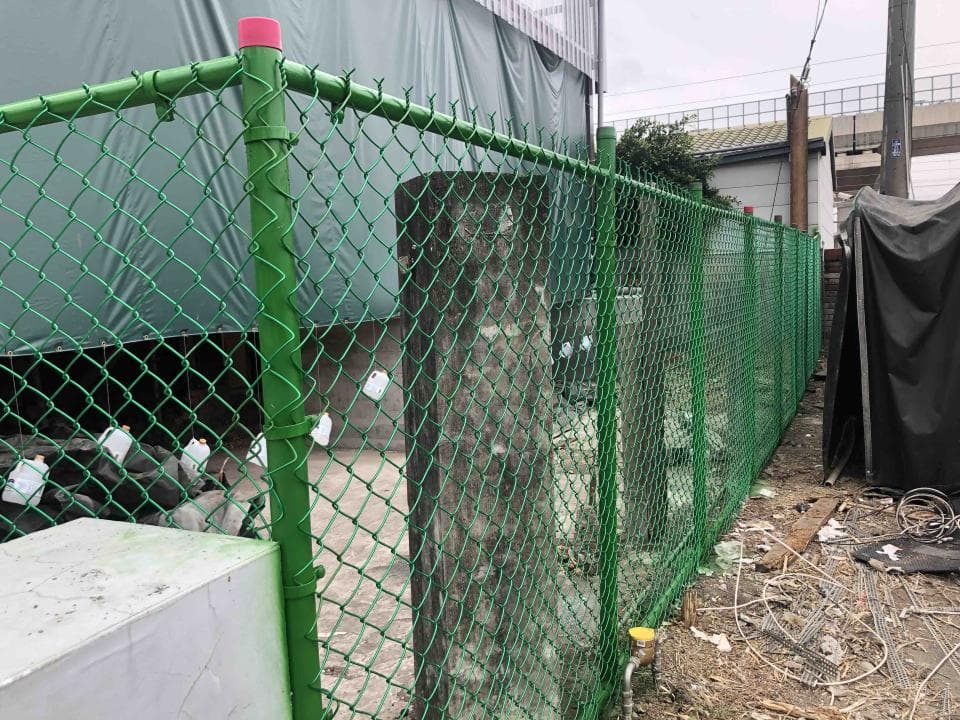 這張照片是一段綠色的鐵絲網圍籬,上面綁著紅色塑膠繩。圍籬看起來很新,而且很堅固。