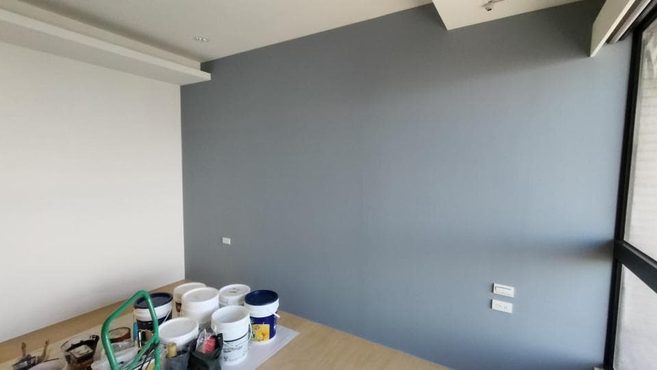 1) 照片顯示一個房間的一角,牆壁是灰色的,地板是木色的,地上放了一些桶子