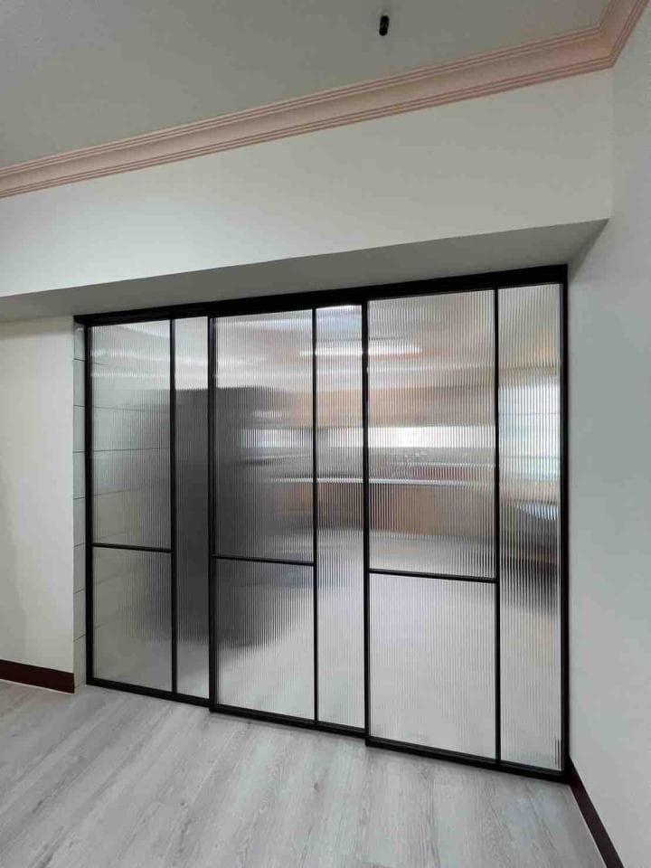 1) 照片顯示一扇由黑色框架組成的玻璃推拉門,玻璃上帶有細條紋