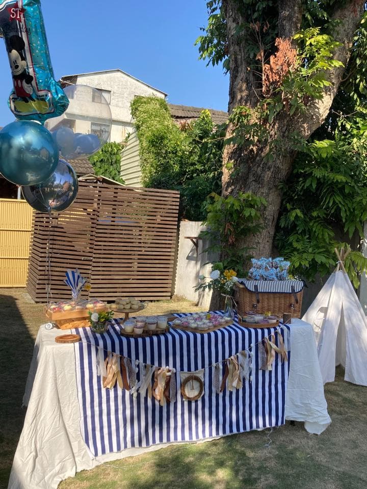 這張照片是一張戶外派對的照片,重點是擺滿甜點的桌子上,有著藍白相間的條紋桌布,上面還有用木頭裝飾的字母,看起來非常可愛。
