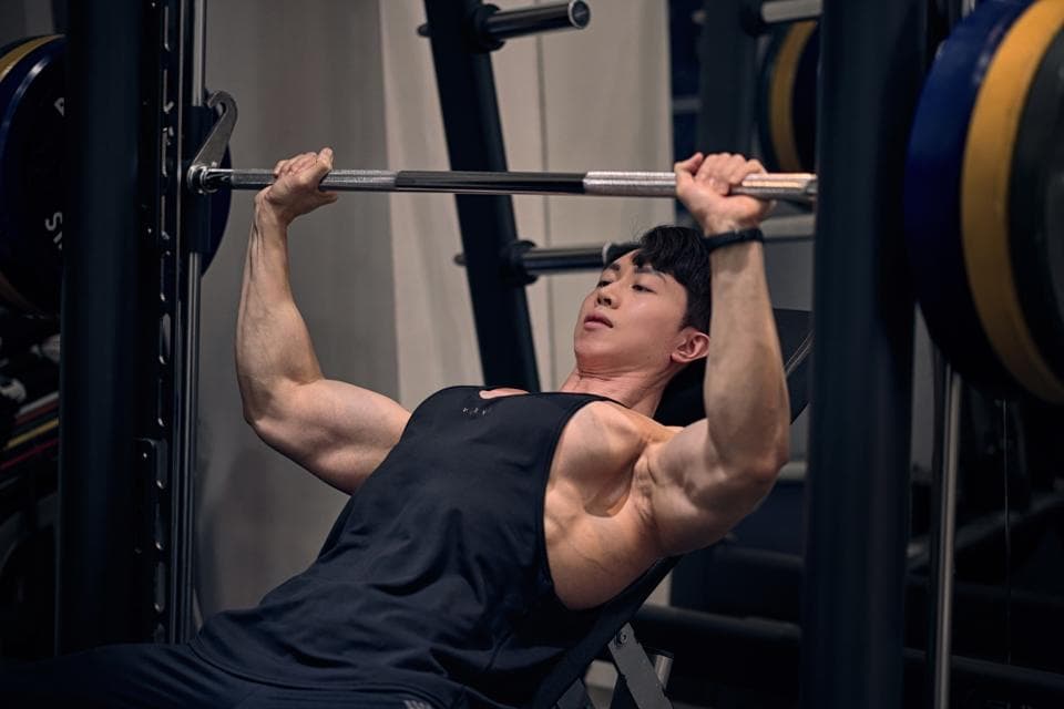 這張照片是一個男子正在舉重。他正在舉起一個槓鈴,並且他的肌肉很發達,展現出他的力量和努力。