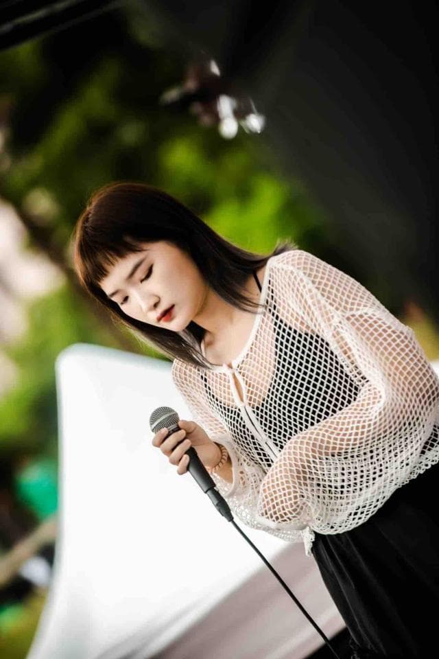 這張「一位年輕女性拿著麥克風唱歌」的照片是。