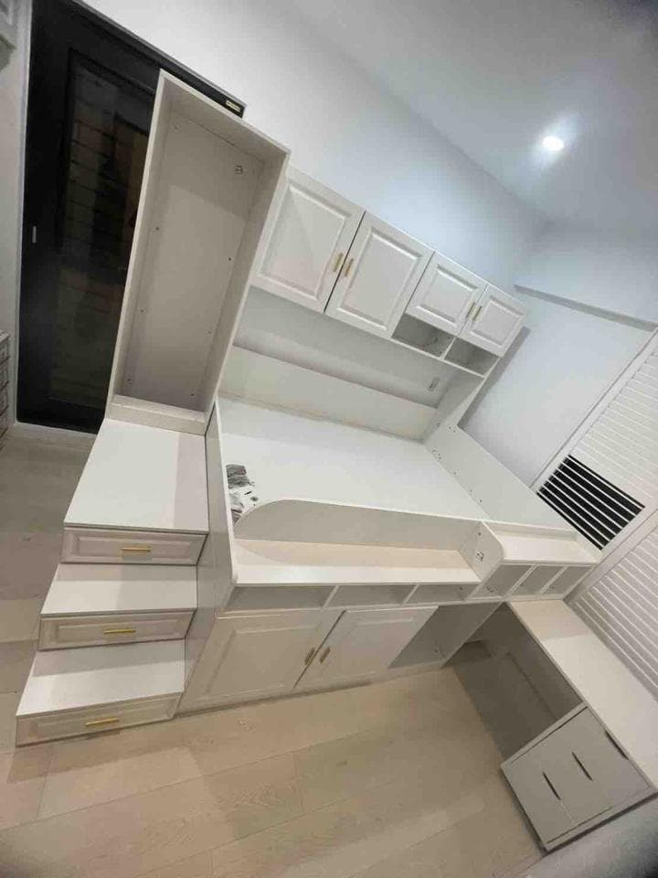 1) 照片顯示一個白色的臥室,其中包含一張床,一個書桌,和一些架子