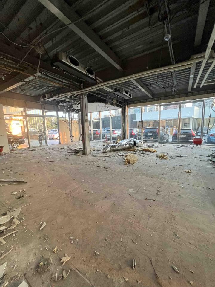 1) 照片顯示一個空曠的建築物內部,天花板上有暴露的橫樑和管道