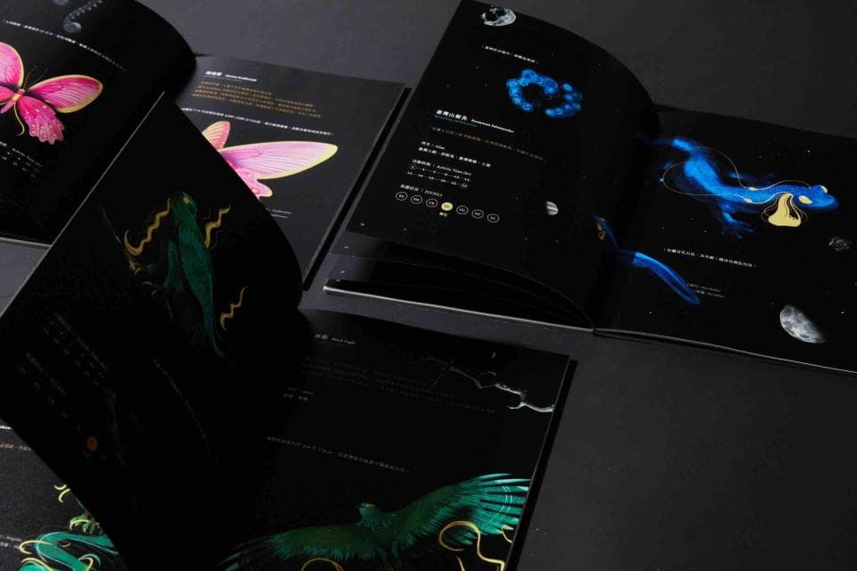 這張「圖冊」的照片是一本黑色封面的書籍,封面印著不同的生物,包括蝴蝶、蜥蜴、鳥和水母。