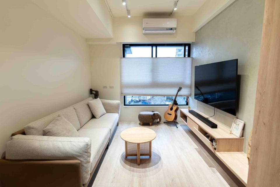 這張「客廳」的照片是一個簡約的現代風格客廳,可以看到沙發、電視、音響設備和一張小桌子。牆壁是淺色系的,傢俱和擺設也都偏向簡潔。