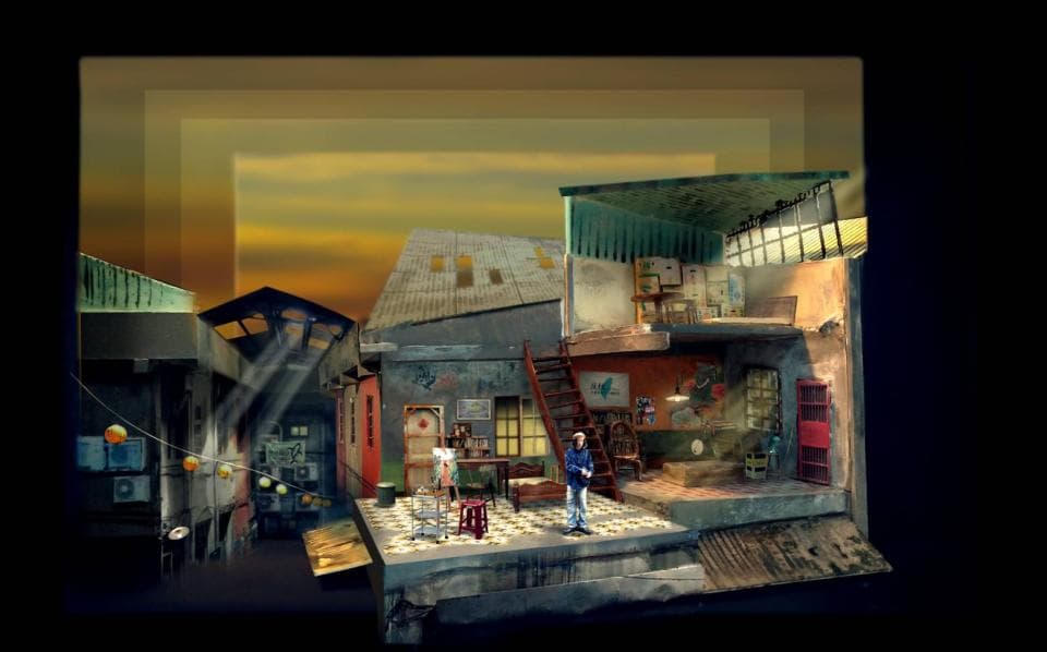 這張「舞臺模型」的照片是一個建在舞臺上的房屋模型,模型裡有一個穿著藍色外套的人站在房子裡,並且可以看到房子內的傢俱、窗戶和樓梯。