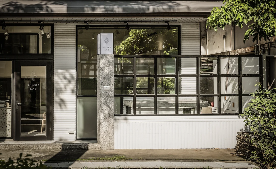 這張「SOUVENIR LAB」的照片是一家簡約風格的商店,店面外觀為白色,帶有黑色框架的玻璃門窗,招牌上印著「SOUVENIR LAB」的店名。