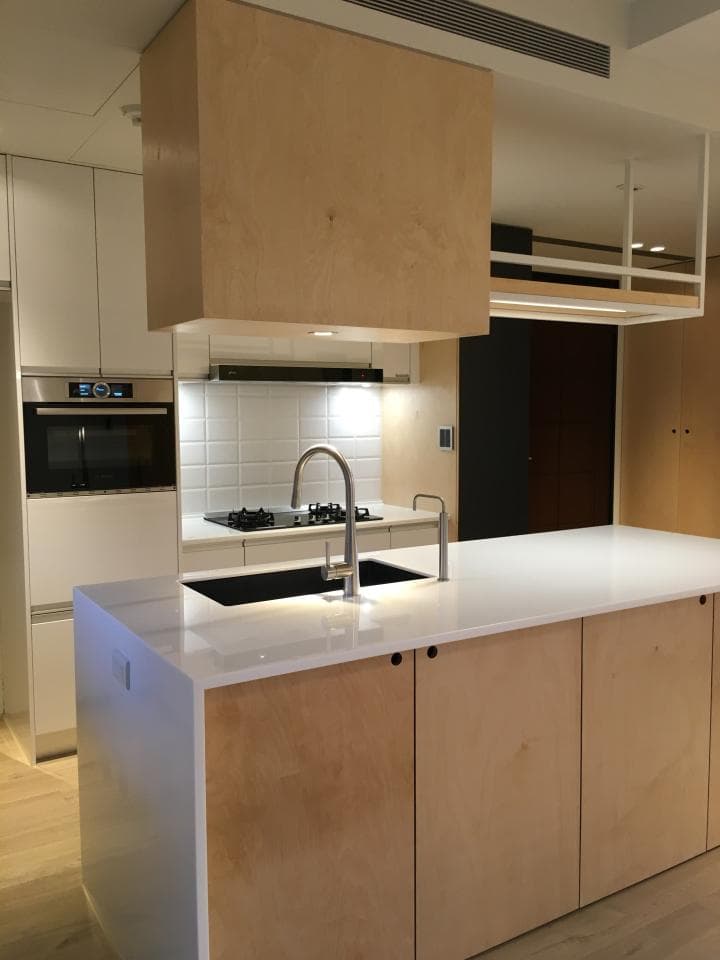 這張照片是一間廚房,最重要的是一個木質的廚房中島,它有白色的檯面和木質的櫃子,看起來很時尚。