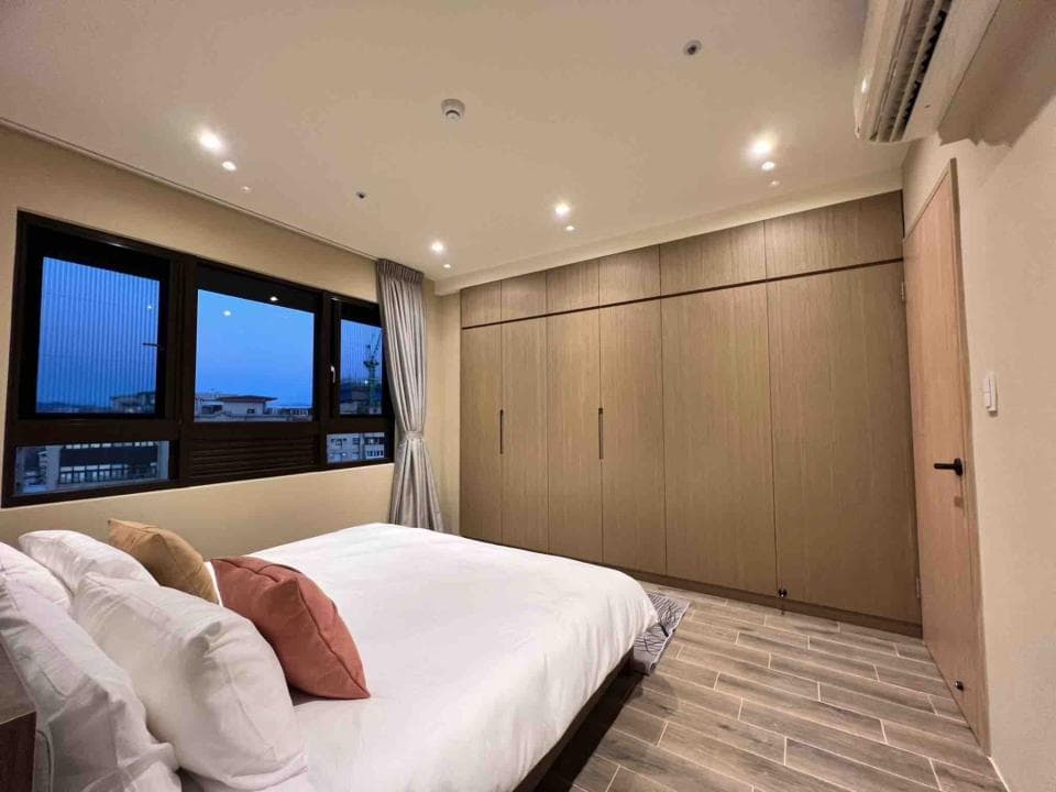 這張「臥室」的照片是一張雙人床,床頭櫃上有裝飾品,旁邊是一扇窗戶,窗戶外可以看到窗外的景色。房間的設計簡潔明亮,讓人感到舒適和放鬆。