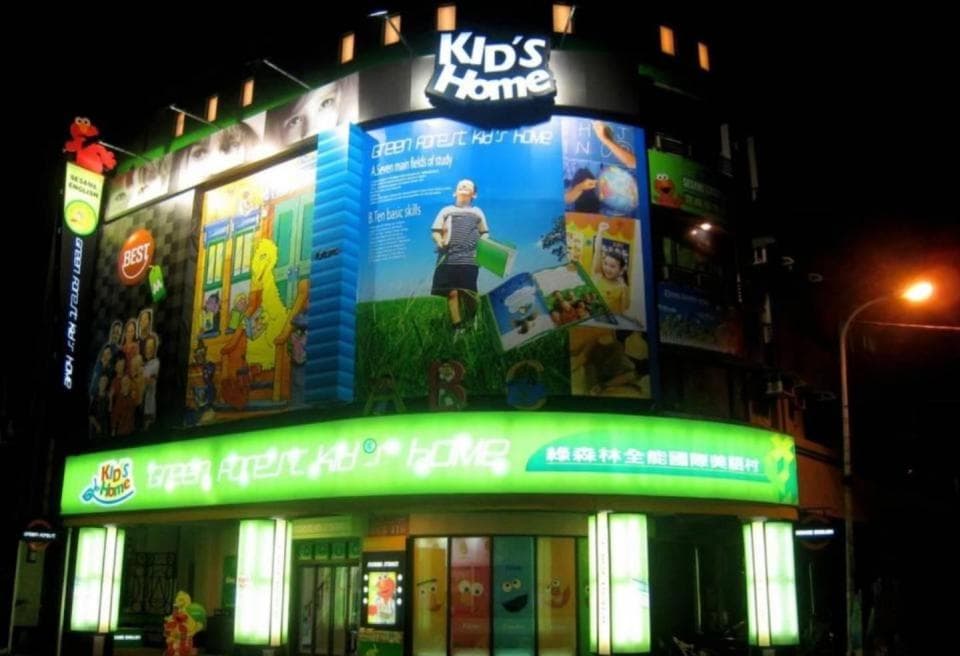這張照片是一間名為「Kid's Home」的商店,店面裝飾著明亮的燈光和大型的廣告看板,展示著商店的品牌和商品。