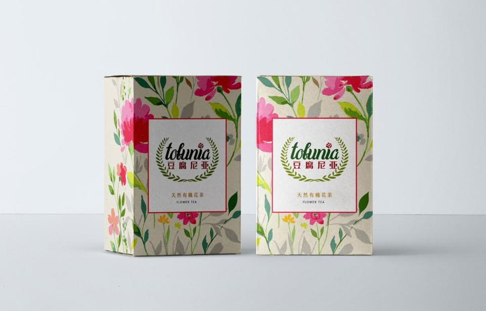 這張照片是兩盒印有花卉圖案的茶葉包裝盒,盒子上印有「tokunia」和「日曦花茶」的品牌和產品名稱。