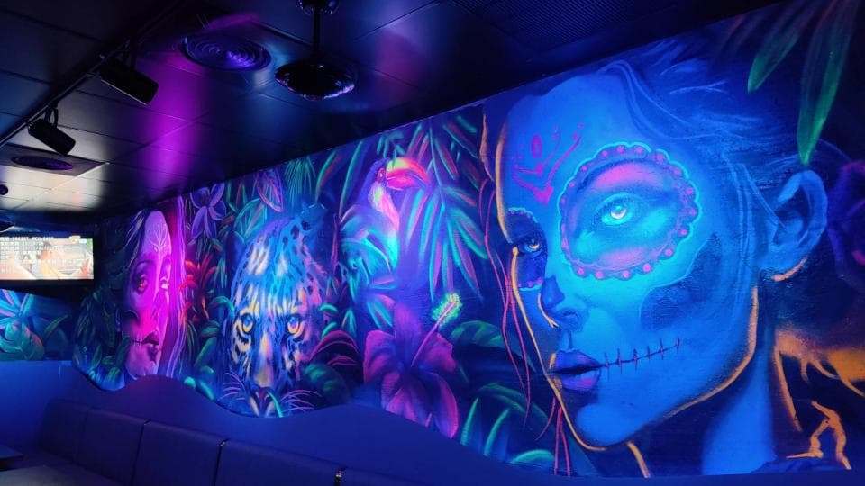 這張「壁畫」的照片是 一個女子臉部特寫,她畫著鮮豔的妝容,背景是茂密的熱帶植物。