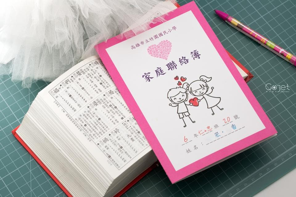 這張「家庭聯絡簿」的照片是,上面印著一個女孩和一個男孩手牽手,旁邊還有很多愛心。