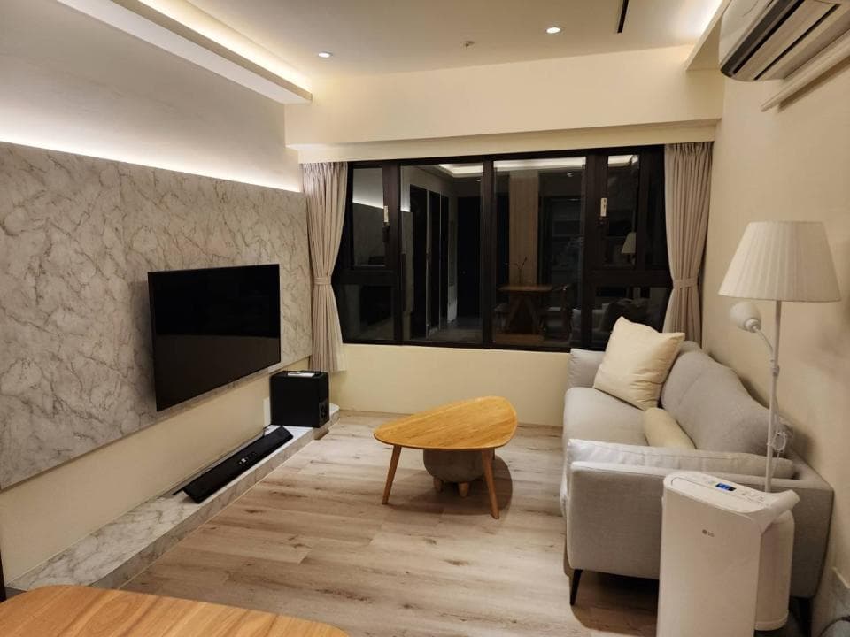 這張客廳的照片是一個舒適的沙發,旁邊有落地燈和一張咖啡桌,牆壁上有一個電視。