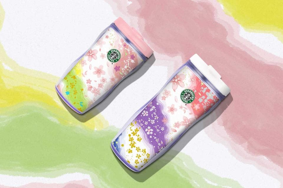這張「星巴克櫻花限定杯」的照片是兩個不同顏色的隨行杯,上面印有櫻花圖案和星巴克的綠色logo。