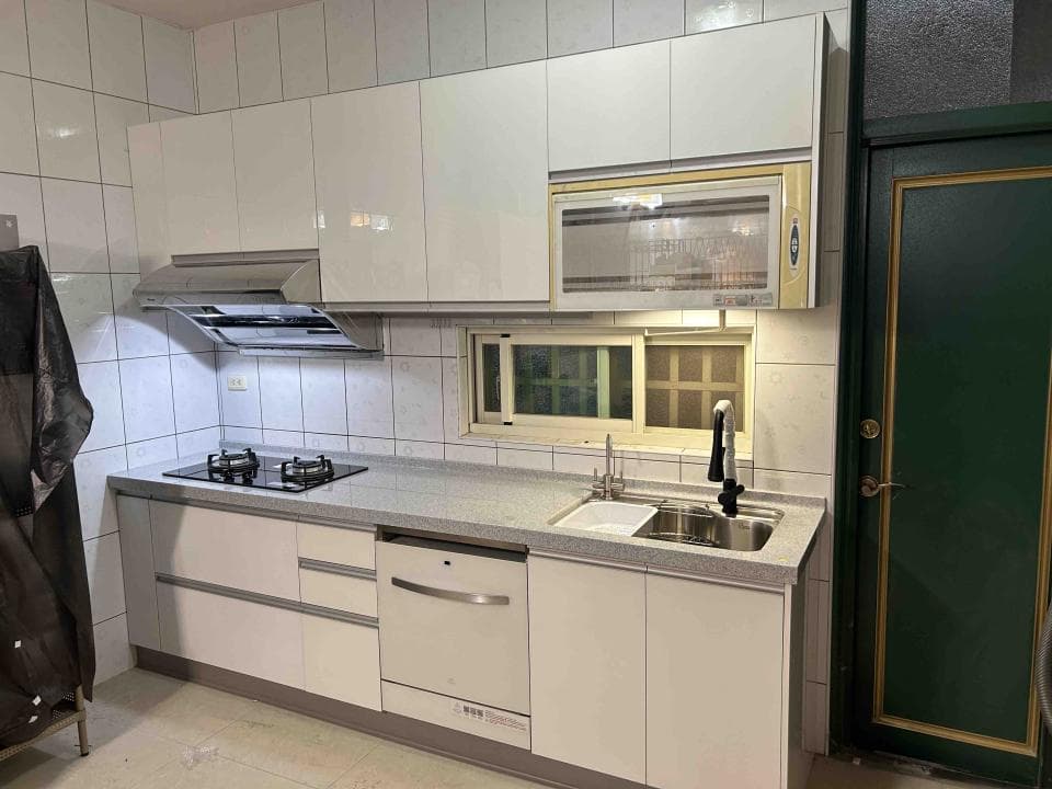 這張廚房的照片是一個白色的現代廚房,配有白色櫥櫃,一個水槽和一個燃氣灶。