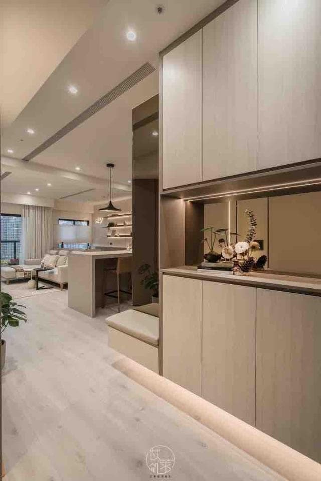 這張「現代家居設計」的照片是,一個以淺色系為主色調的客廳,採用了木質地板,並在牆上設置了壁櫃,櫃子下方裝有燈帶,營造出簡約、明亮的空間感。