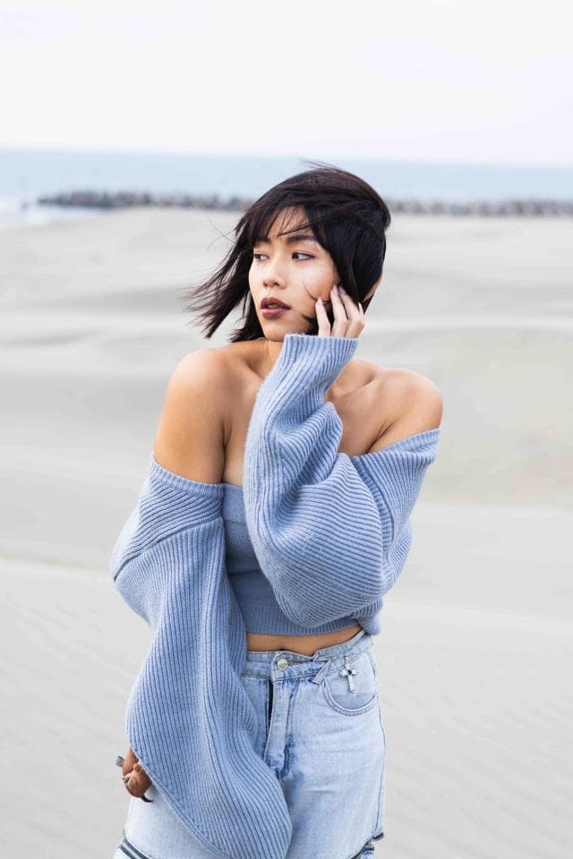 這張「一位年輕女子穿著淺藍色針織衫,站在沙灘上」的照片是。