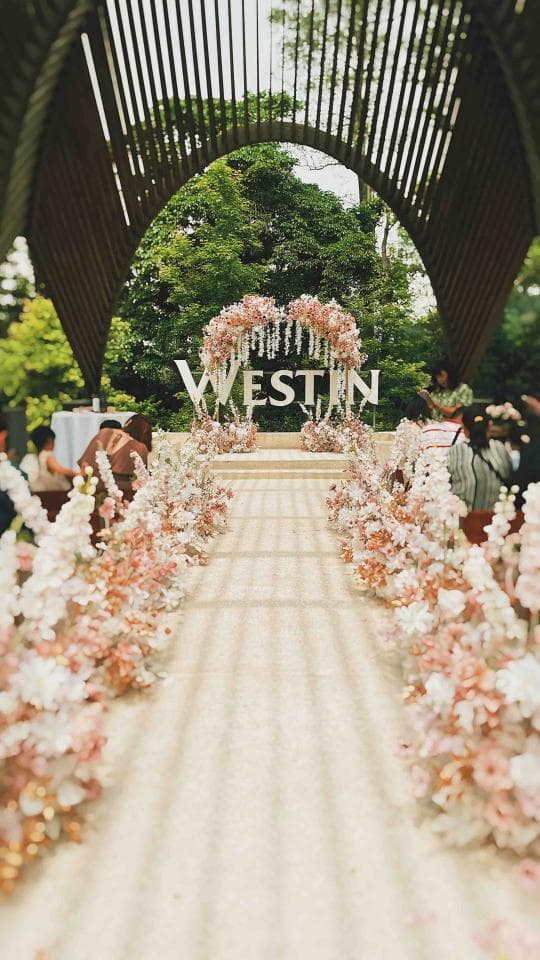 這張「婚禮」的照片是一條用鮮花裝飾的走道,走道兩旁都佈滿了白色的花朵,中間是一個寫著「WESTIN」的牌子。