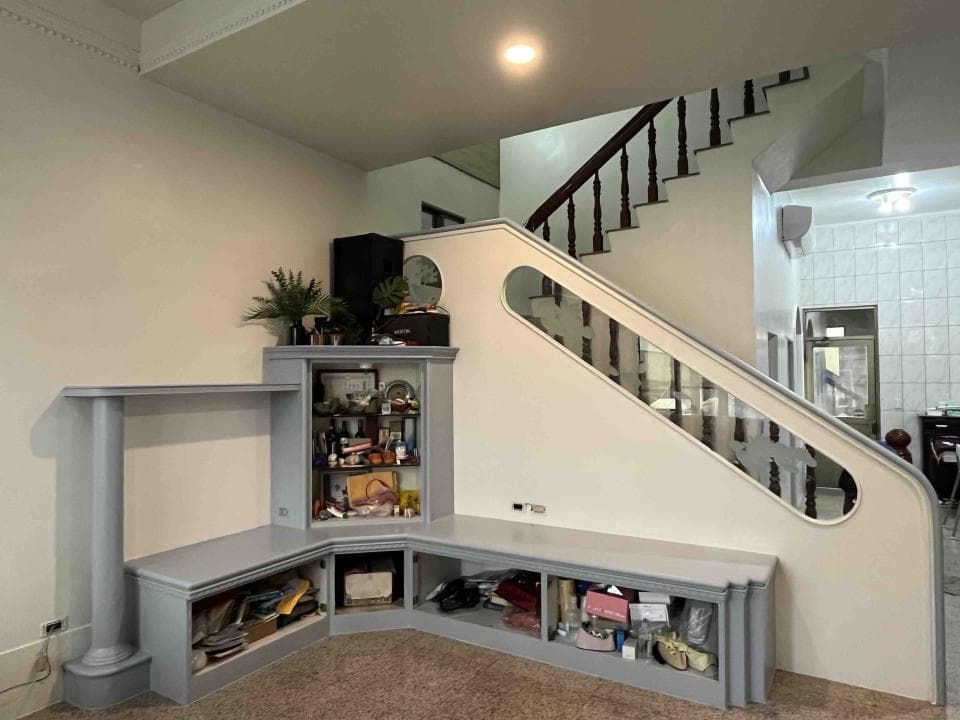 這張照片是一個現代化的客廳,最重要的是房間的牆壁上有一個白色扶手的樓梯,樓梯的設計很有特色,扶手下方還有一個圓形的玻璃窗,為空間增添了一份優雅和通透感。