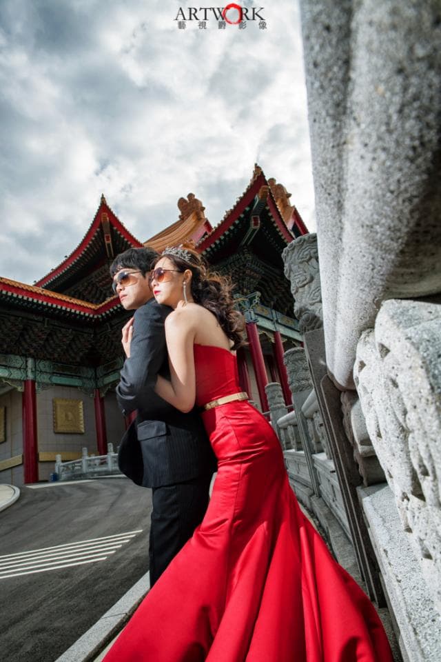這張「婚紗照」的照片是一對新人在中國傳統建築前拍攝的。新娘穿著紅色婚紗,新郎穿著西裝,兩人深情相擁,背景是傳統的中國建築,畫面充滿幸福浪漫的氣氛。