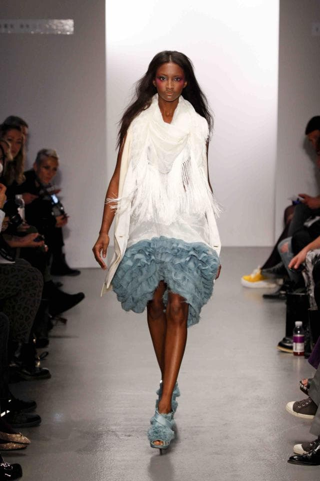 這張照片是一個穿著白色毛衣和藍色蓬蓬裙的年輕女孩。