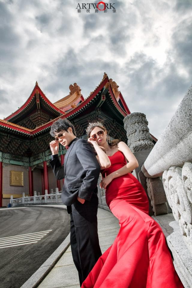 這張「婚紗」的照片是一對新人,穿著西裝和紅色的婚紗,站在中國宮殿前。