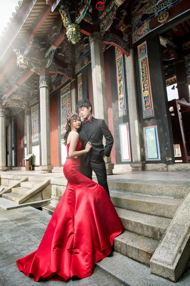 這張「婚紗照」的照片是一對新人在古老的廟宇前拍攝的,新娘穿著紅色婚紗,新郎則穿著黑色西裝,他們互相依偎著,看起來非常幸福。