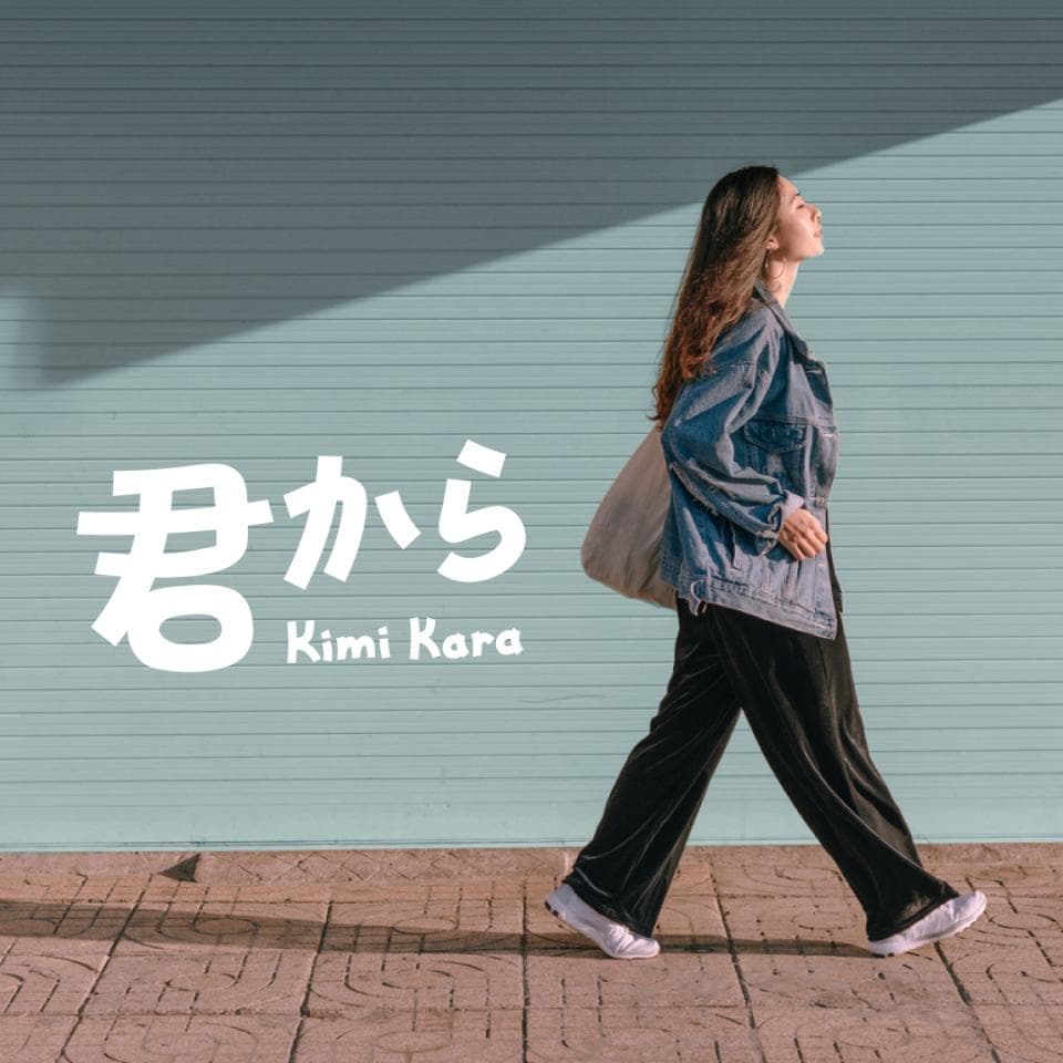 這張「君から」的照片是一個女孩走在路上的背影,她穿著牛仔外套和黑色褲子,背著一個白色包包,看起來很時尚。