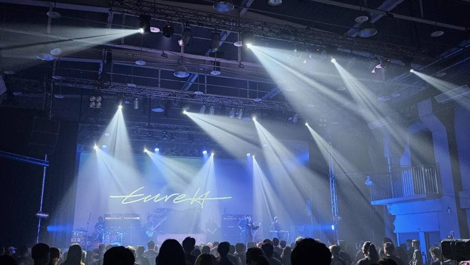 這張照片是一場音樂會,舞臺上有很多燈光照射在舞臺上,觀眾席上坐滿了人,場面非常熱鬧。