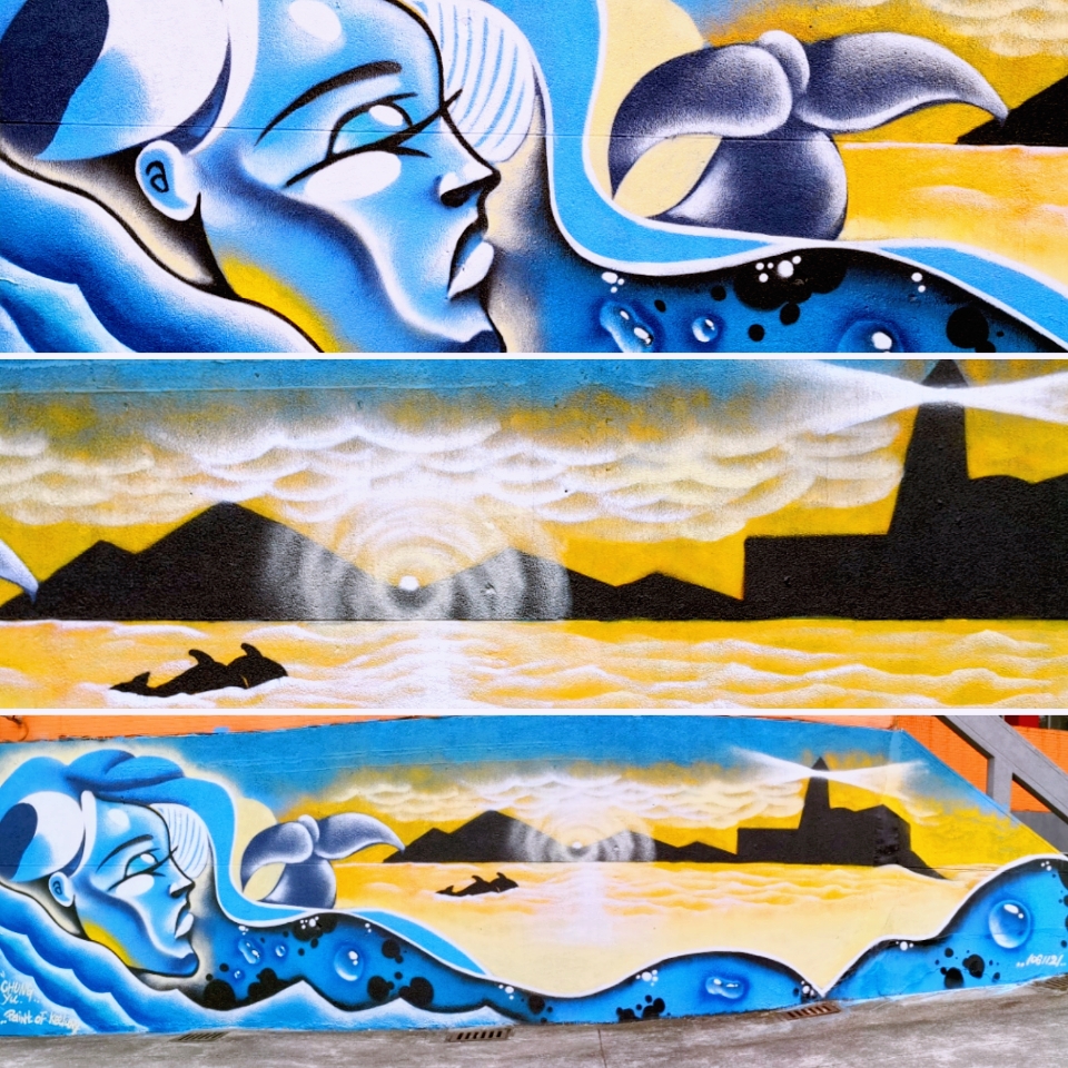 這張「壁畫」的照片是 一個女人在水裡游泳的圖畫,她的背後有魚和海浪,牆上還有山、雲彩和燈塔。