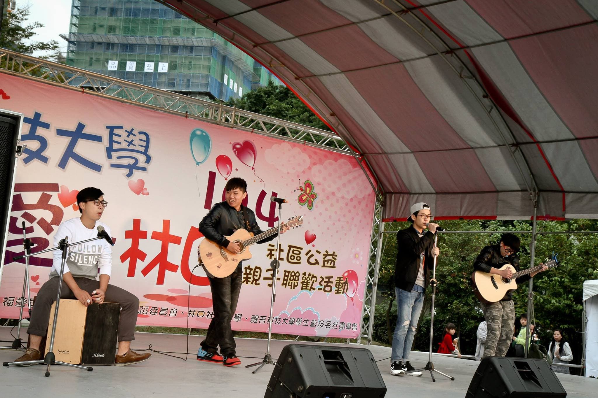 這張「街頭藝人表演」的照片是三位年輕人正在戶外表演,其中兩位正在彈吉他,一位正在唱歌。