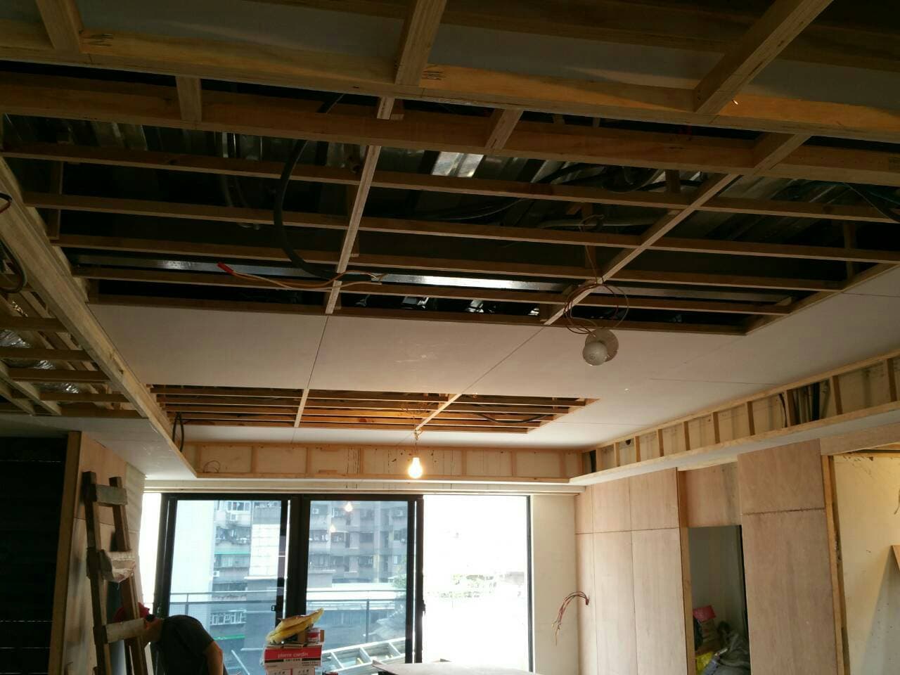 這張照片是一間正在裝修的房間,房間裡的天花板正在施工,可以看到木條搭建的框架以及部分已安裝的石膏板。