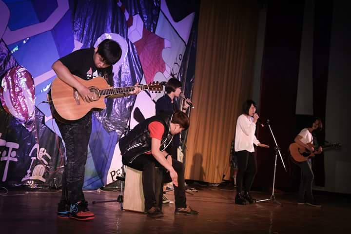 這張「樂團表演」的照片是一個樂團在舞臺上表演,主唱正在唱歌,吉他手正在彈吉他,鼓手正在打鼓。