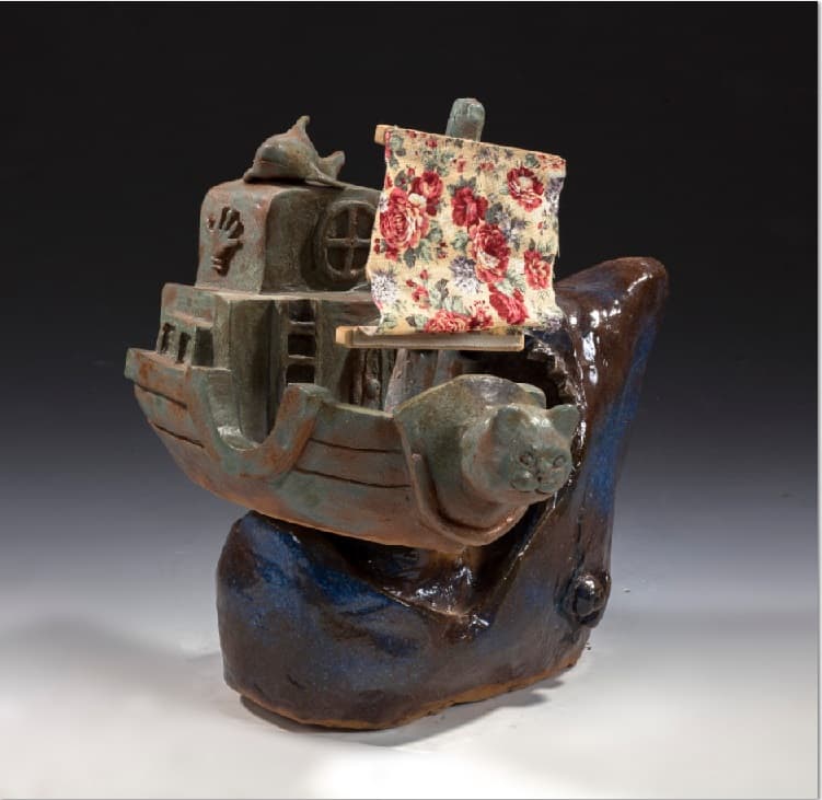 這張「陶瓷雕塑」的照片是一艘小船被巨浪吞沒的景象。船上有一面印著紅花的布帆,船頭有一隻海豚,船身則被巨浪的嘴巴咬住。