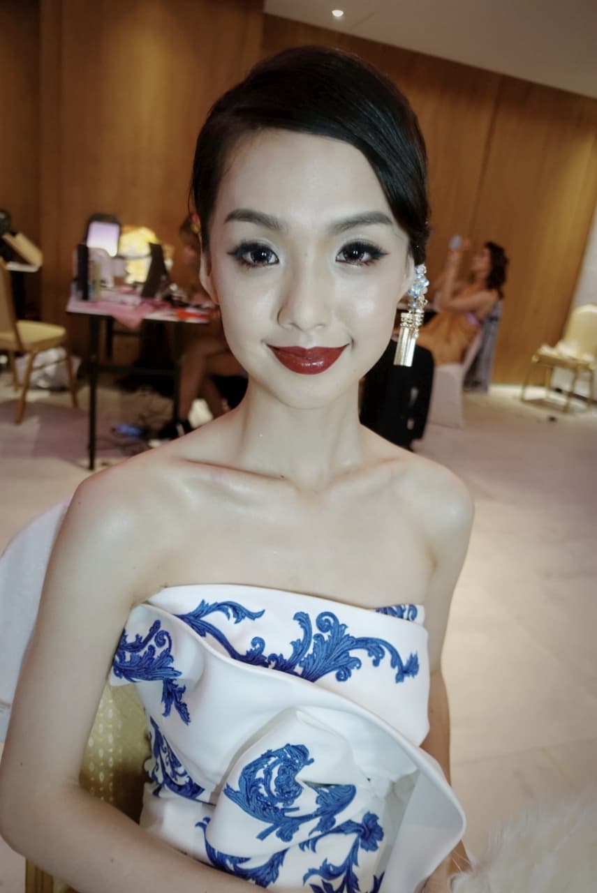 這張「美麗新娘」的照片是,一位身穿白色禮服,上面有藍色花紋,並戴著金耳環的女孩。