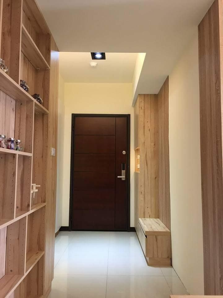這張照片是一間現代化的玄關,最顯眼的是木質地板和牆面,以及中間一扇深色的木門。