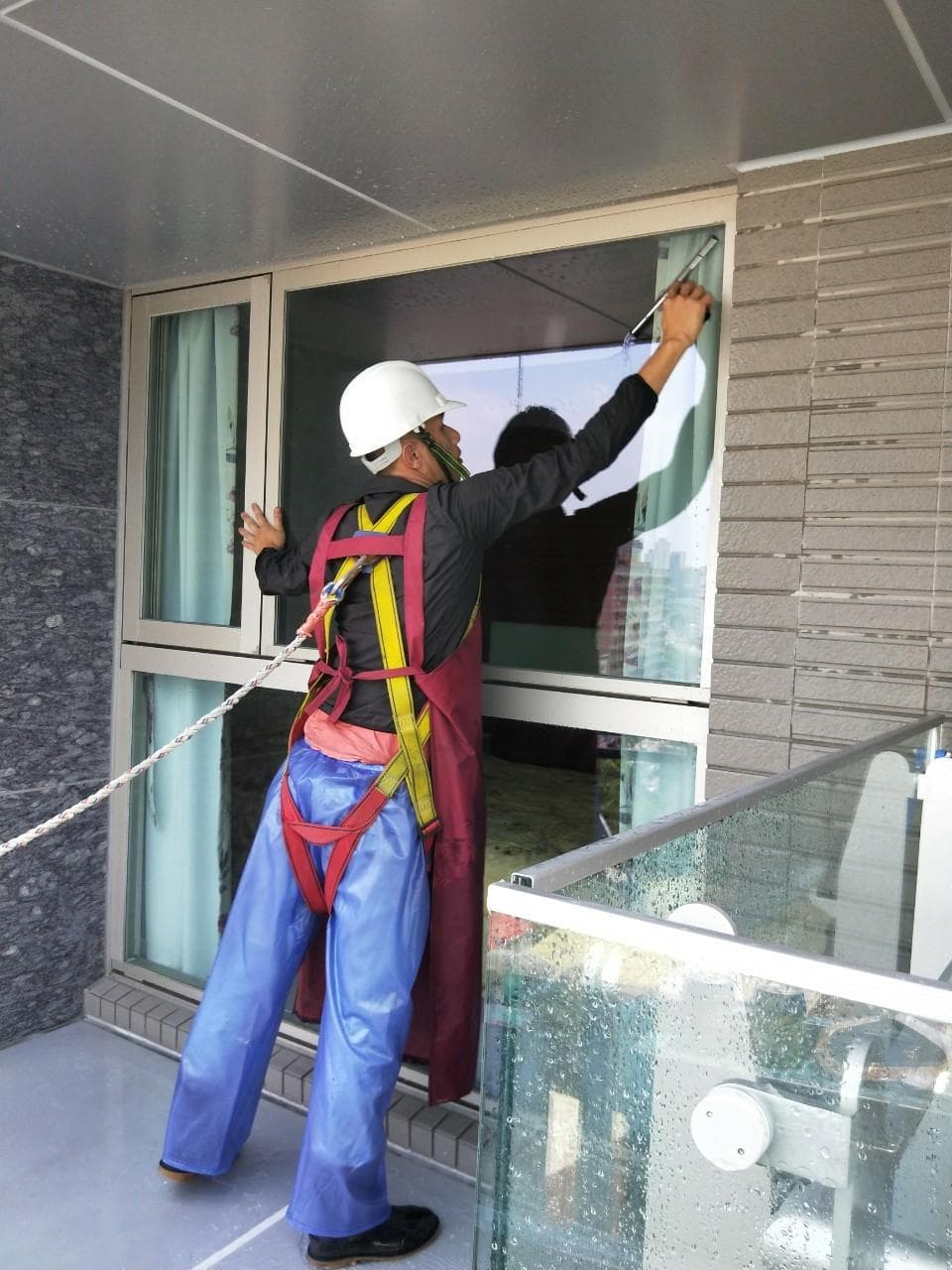 1) 照片顯示一名穿著安全帶和安全帽的男性工人正在清洗高樓的窗戶