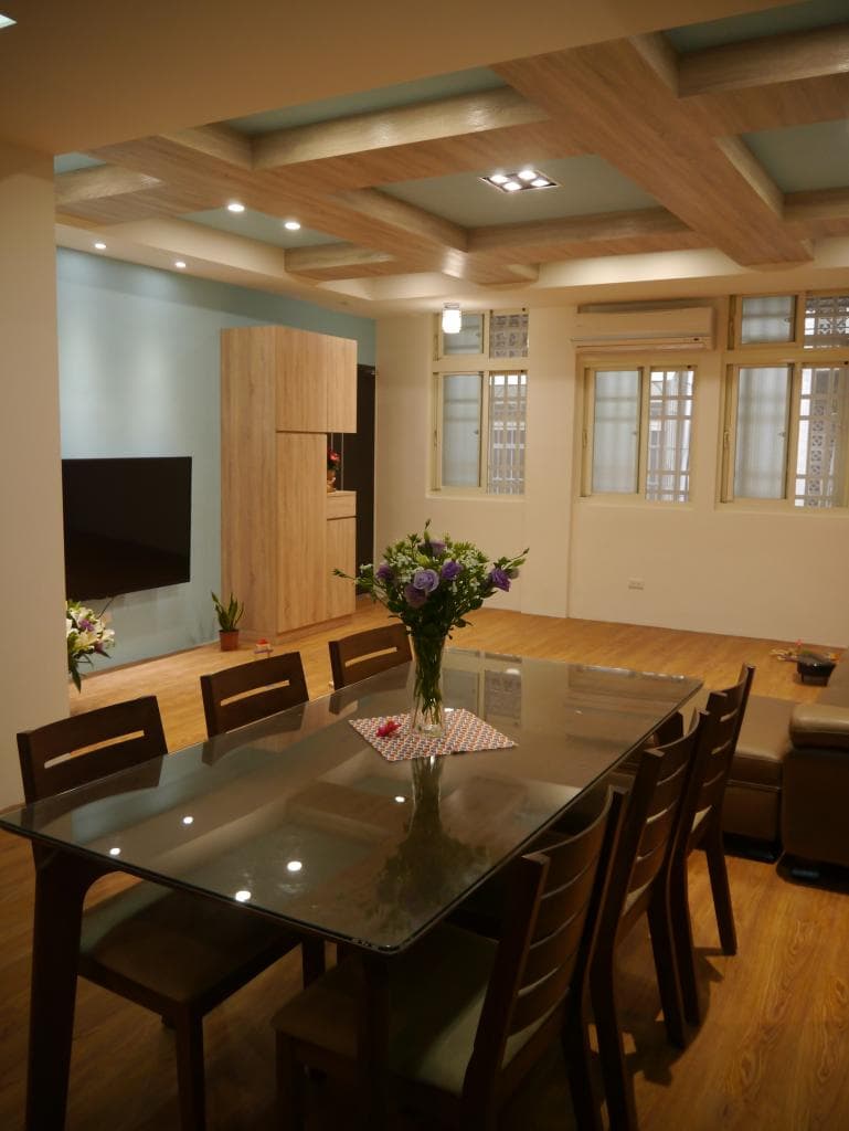 這張照片是一個現代化的餐廳,最重要的是玻璃餐桌,上面放著一束鮮花和一個玻璃花瓶,桌子的四周擺放著木質餐椅,整個空間看起來舒適而優雅。