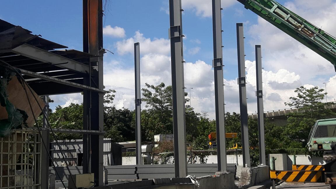 1) 照片顯示一座建築物的鋼樑支架,背景有藍天白雲和樹木